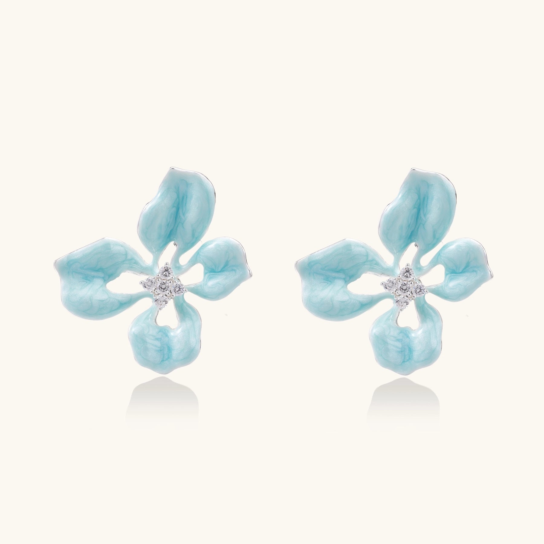 Turquoise blue enamel flower earrings with crystal centers and gold-plated brass posts on white background.